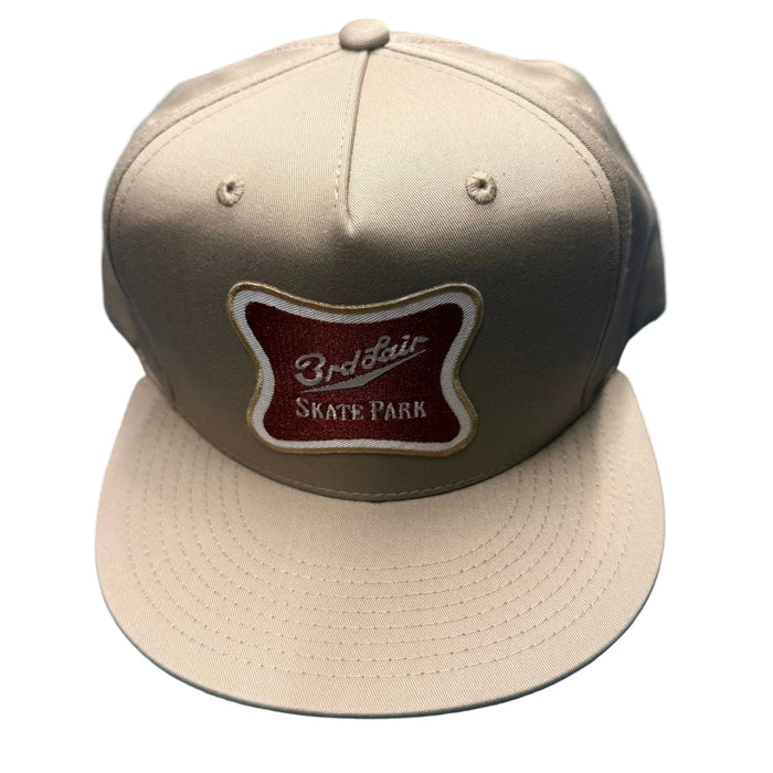 Beige cap with a brown and white logo on a blue textured background