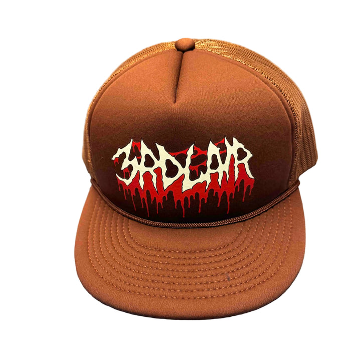 Brown cap with 'Badlar' logo on a gray surface