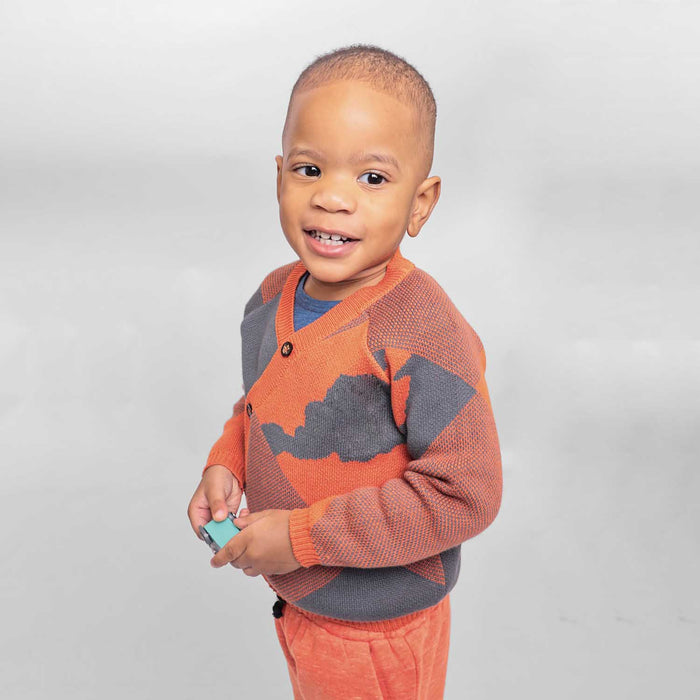 Baby wearing a blue and orange knitted cardigan during playtime