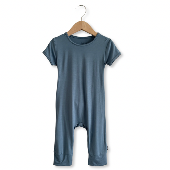 A gray baby romper with short sleeves and long legs, hanging on a wooden hanger.